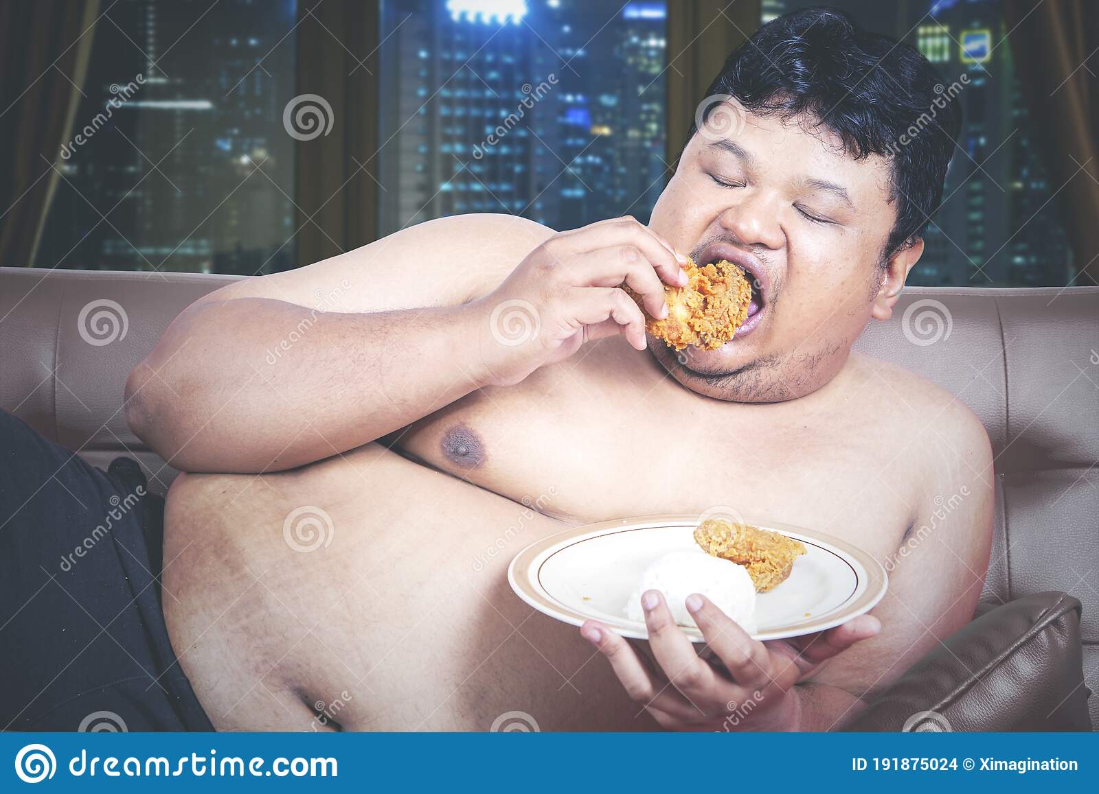 close-up-starving-fat-man-eating-plate-fried-chicken-sitting-couch-night-time-shot-home-close-...jpg