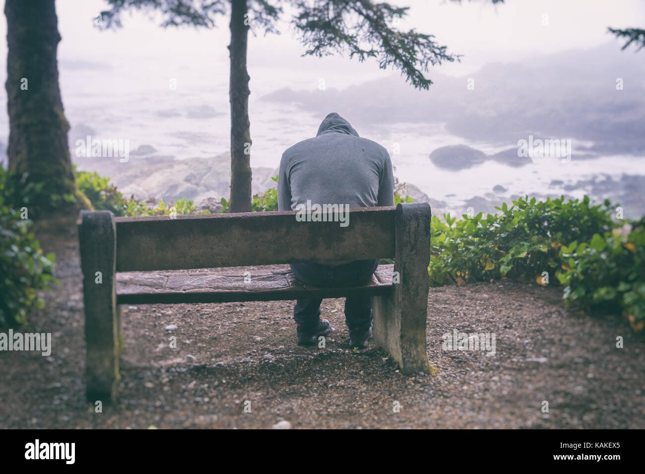 sad-and-lonely-man-sitting-on-bench-overlooking-sea-on-vancouver-island-KAKEX5.jpg